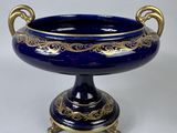 a blue vase with gold decoration on it on a stand