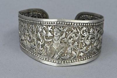 a close up of a silver bracelet with a bird on it