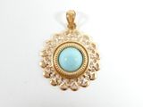 a close up of a gold pendant with a turquoise stone