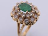 a close up of a ring with a green stone surrounded by diamonds