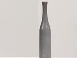 grey vase sitting on a white surface with a shadow of a person