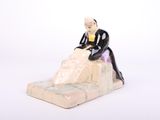 une figurine d'un homme assis sur un rocher