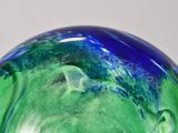 a green and blue glass sculpture on a white surface