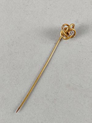 a close up of a gold pin with a knot on it