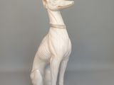 une statue blanche représentant un chien assis sur une table