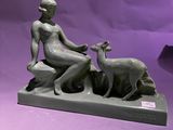 statue d'une femme assise sur un rocher avec une chèvre, sur fond violet