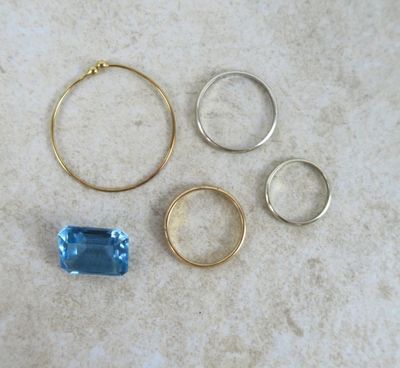 trois bagues et une bague sertie d'une topaze bleue, posées sur une table