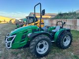 un tracteur vert garé dans un champ, près d'un mur