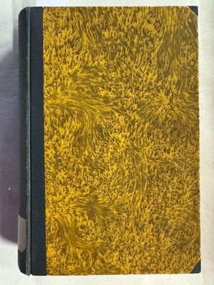 un vieux livre à la couverture jaune posé sur une surface blanche