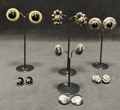 several pairs of earrings are displayed on a stand on a gray surface