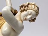 statue of a woman holding a tennis racquet in her right hand