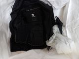 a black jacket and a white bag on a bed