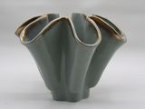 a green vase with a gold rim sitting on a white surface