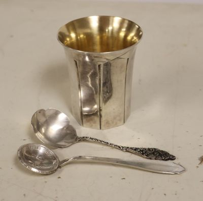 a silver cup with spoons and a spoon on a table