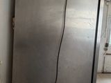 a silver refrigerator in the corner of a room with tile flooring