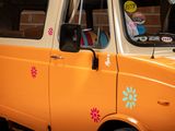 an orange van with flowers painted on the side of it