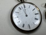 a silver pocket watch with roman numerals on it