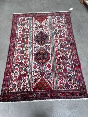 un tapis oriental exposé dans une pièce où se trouve une chaise
