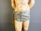 une statue en bois représentant un homme avec une serviette autour de la taille