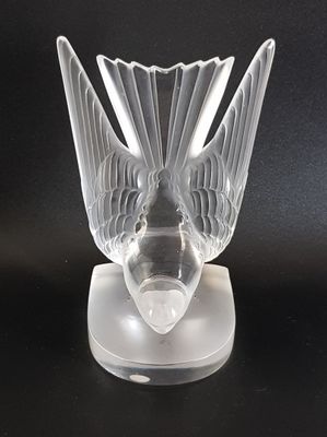 a clear glass vase with a bird on top of it