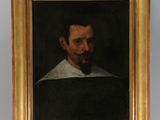 painting of a man with a beard and a white collar on a wooden easel