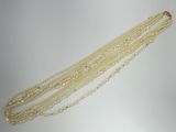 a close up of a necklace with pearls on a white surface