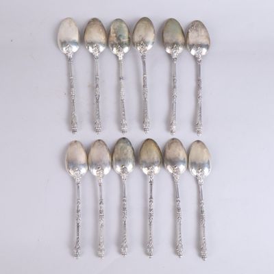 six cuillères en argent sont disposées en ligne sur une surface blanche