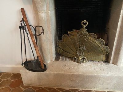 une cheminée avec un manteau de cheminée et un balai posé devant