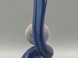 a blue and white vase with a rock on top of it