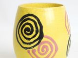 a yellow cup with black and pink swirls on it
