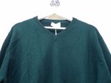 a green sweater hanging on a hanger on a white wall