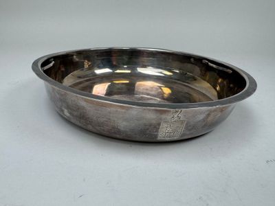 une plaque d'argent antique sur une surface blanche