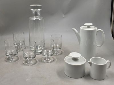 de nombreux verres, un pichet et des tasses sur la table