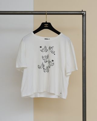 un t-shirt blanc orné de papillons noirs, suspendu à un cintre