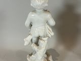 a small statue of a boy with a bird on a pedestal