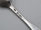 a silver spoon with a cross on it sitting on a table