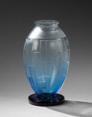 un vase en verre bleu posé sur un socle noir