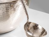 a silver bowl with a spoon in it on a table