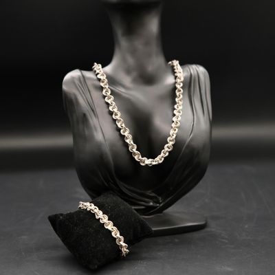 a black and white photo of a mannequin with a necklace and a pair of gloves