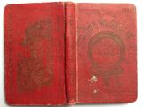 an old book with a red cover sitting on top of a table