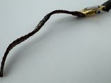 a metal stick with a gold colored handle on a white surface