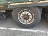 a green truck with a flat tire parked in a parking lot