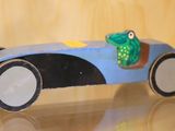 une petite voiture avec une grenouille posée dessus, posée sur une table