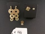 deux paires de boucles d'oreilles en or et une étiquette sur un fond noir
