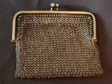 a small metal purse with a chain handle on a black surface