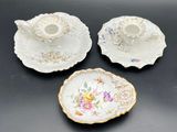three pieces of porcelain with floral designs on them on a table