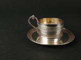 une tasse et une soucoupe argentées posées sur une table noire