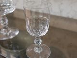 three wine glasses sitting on a glass shelf next to a vase