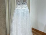 une robe posée sur un mannequin, avec des fleurs en arrière-plan