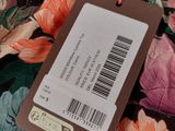 une étiquette sur un tissu à fleurs coloré, accompagnée d'une étiquette de prix